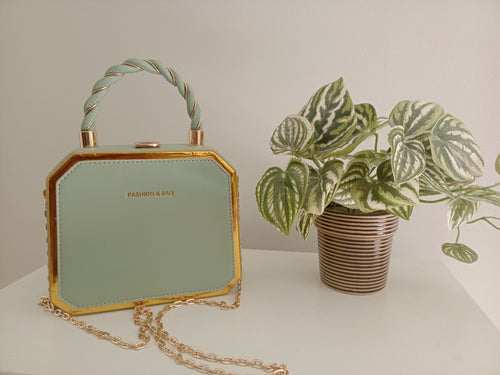 mint green faux leather handbag with gold trim and a twisted rope handle.